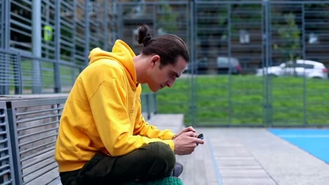 Young man using smartphone for playing game online on modern sport area outside Video stock 135667281