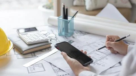 Young man using Smartphone plotting a system of building structures in bluepr Fotos de archivo