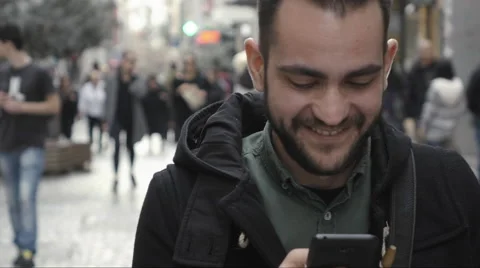Young man using smartphone in public commercial street slomo dolly Stock Footage 60454540