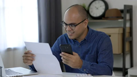 A young man is using a smartphone to scan the bill to calculate his income and e Stock Footage 153203311