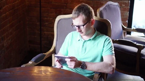 Young man using smartphone sitting in cafe in city Stock Footage 73126797