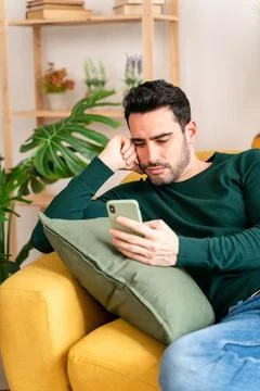 Young man using smartphone on sofa Stock Photos