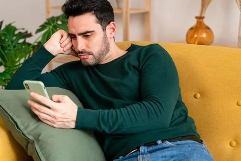 Young man using smartphone on sofa Stock Photos