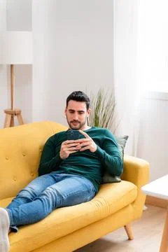 Young man using smartphone on sofa Stock Photos