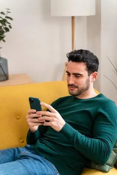 Young man using smartphone on sofa Stock Photos