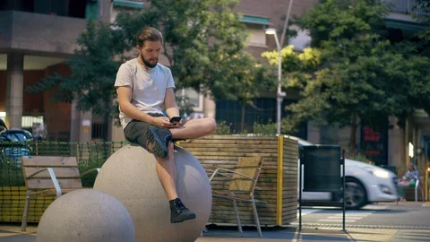Young man using smartphone in square at evening Stock Footage 118941076
