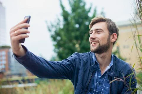 Young man using smartphone to take a selfie outdoors Stock Photos