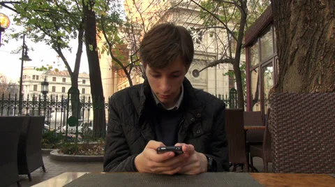 Young man using a smartphone on a terrace cafe, text messaging, outdoors 스톡 동영상 32638954