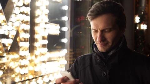 Young man using smartphone on a urban street in evening standing near storefront Stock Footage 83630720