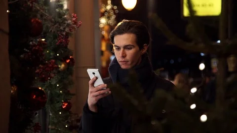 Young man using smartphone on a urban street in evening standing near storefront Stock Footage 83630774