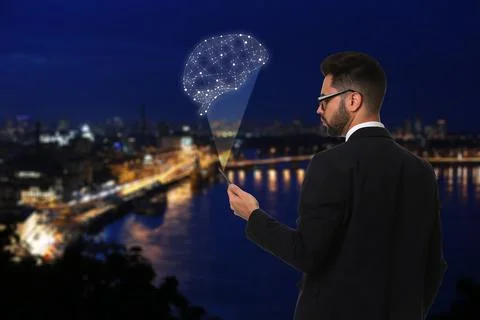 Young man using smartphone with virtual image of brain and night cityscape on 스톡 사진