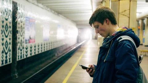 Young man using smartphone waiting for subway train Stock Footage 86311363