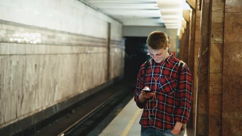 Young man using smartphone waiting for subway train at metro station. Stock Footage 90762553