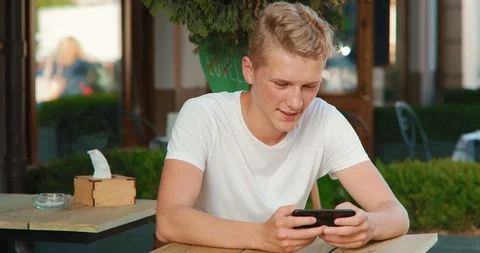 A young man is using a smartphone while sitting in a cafe Stock Footage 91491435
