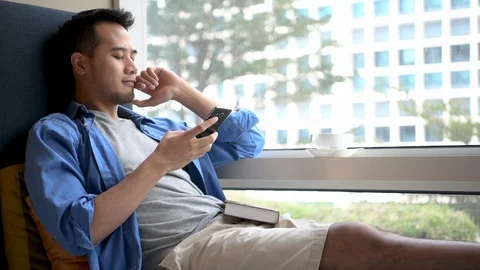 Young man using smartphone  while sitting on sofa at home . Stock Footage 125951489