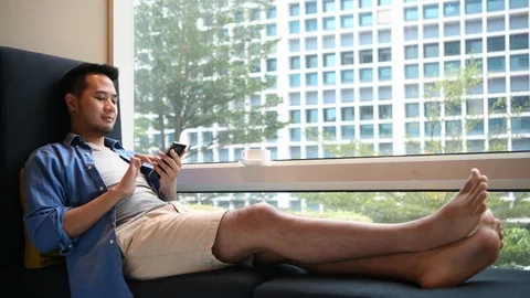 Young man using smartphone while sitting on sofa at home . Stock Footage 126644204