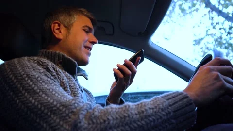 Young man using a smartphone while driving a car with one hand Stock Footage 147149038