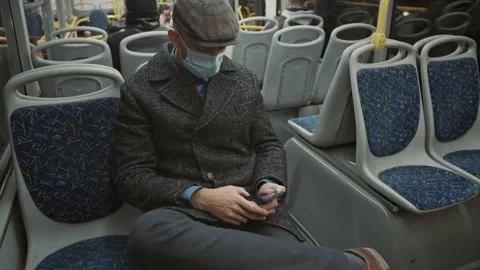 Young man using a smartphone while traveling on a bus. Masked transit concept. Stock Footage 167320628