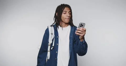 Young man using smartphone while standing in a casual studio setting with b.. Stock Footage 313951172