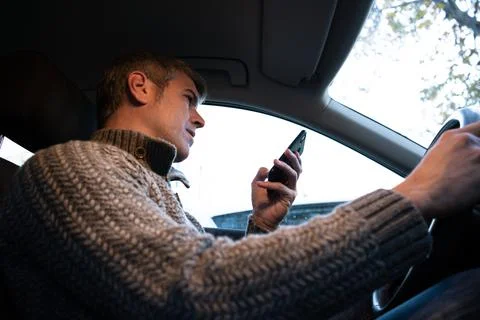 Young man using a smartphone while driving a car with one hand Stock Photos