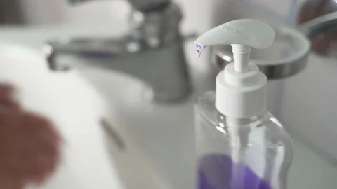 Young Man Using Soap Dispenser, then Washing Hands in background Stock Footage 139056675