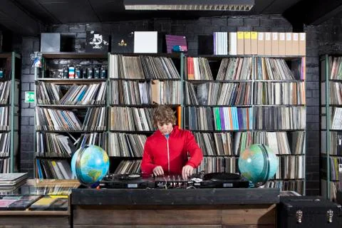 A young man using a sound mixer and DJ decks at a record store Stock Photos