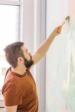 Young man using spatula and plastering of wall with white fresh finishing putty Stock Photos