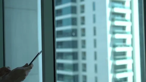 Young man using tablet computer standing by window at home Stock Footage 70718082