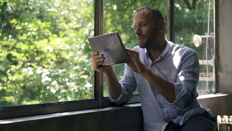 Young man using tablet computer by window at home, 4K Stock Footage 73152684