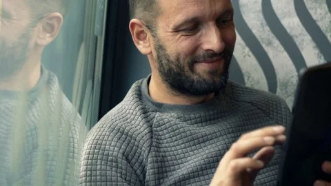 Young man using tablet computer sitting in cafe by the window Stock Footage 75733208