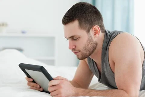 Young man using a tablet computer while lying on his belly Stock Photos
