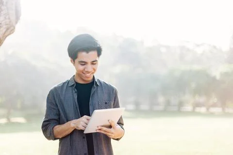 Young man using tablet device in a park Stock Photos