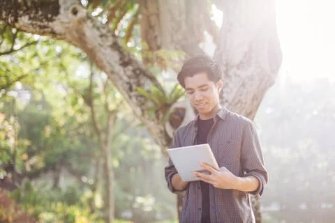 Young man using tablet device in a park Stock Photos