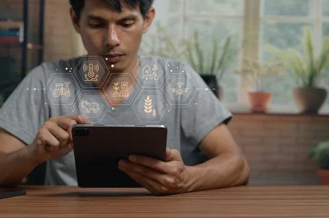 Young man using tablet with digital technology icons in bright modern home Stock Photos