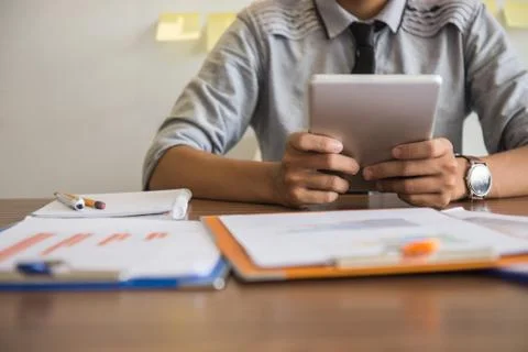 Young man using tablet with financial report on desk Stock Photos