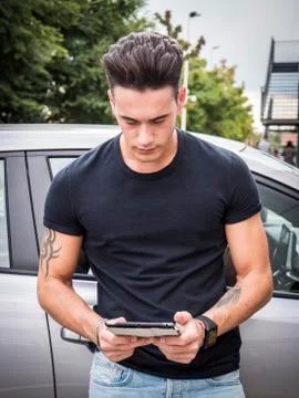 Young man using tablet PC leaning on car Stock Photos