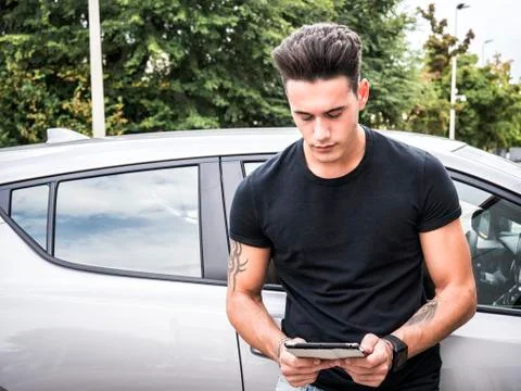 Young man using tablet PC leaning on car Stock Photos