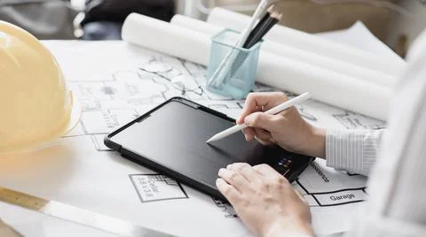 Young man using tablet plotting a system of building structures in blueprints Stock Photos