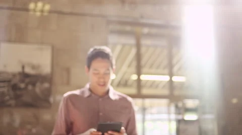 A young man using a tablet at a railroad terminal and smiling at the camera Vidéo 57509947