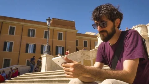 Young Man using tablet sitting on steps in Rome Square Stock-Footage 77557847