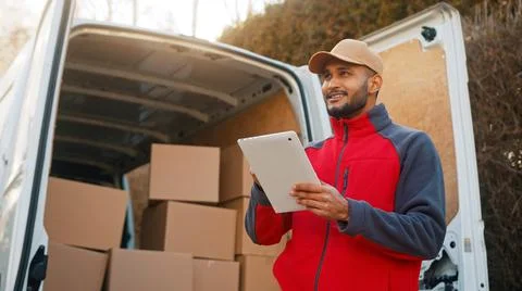 Young man using tablet to view information about the parcel. Delivering the Stock Photos