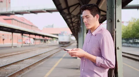 A young man using a tablet while waiting for a train Stock Footage 57509241