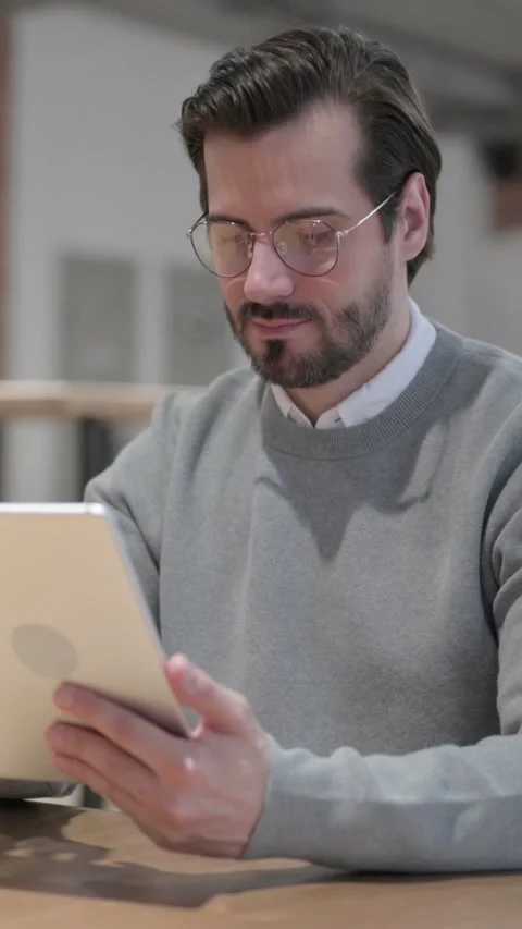 Young Man using Tablet while Sitting in Office, Vertical Video Stock Footage 339580947
