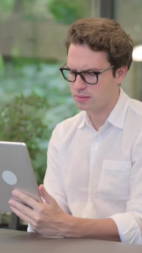 Young Man Using Tablet while Sitting in Modern Office, Vertical Video Stock Footage 340032411