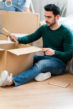 Young man using tablet while unpacking boxes at home Stock Photos