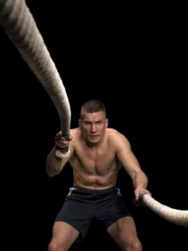 Young man using training ropes on black background Stock Photos