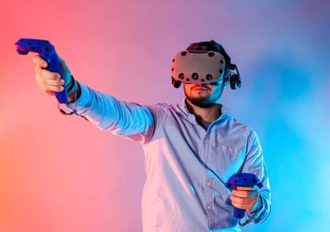 Young man using the virtual reality glasses and two gamepad Stock Photos