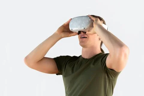Young man using virtual reality headset. Isolated on gray background. Stock Photos