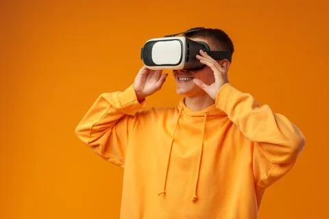 Young man using virtual reality headset against yellow background Stock Photos