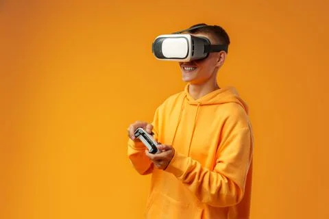 Young man using virtual reality headset against yellow background Stock Photos